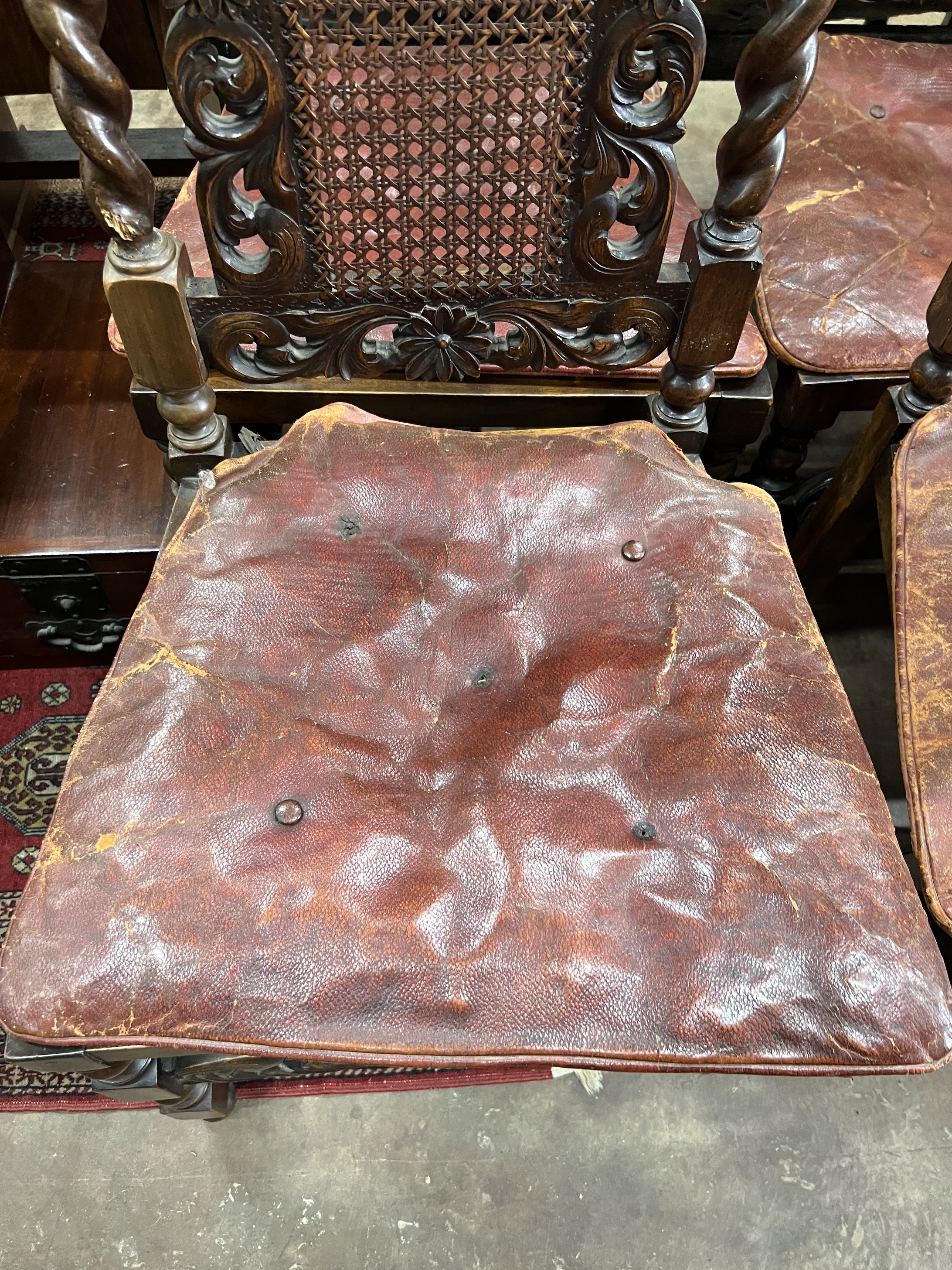 A set of six Jacobean revival carved caned beech dining chairs with leather squab seats